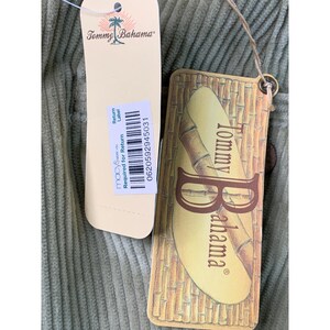 May include: Close-up of a light green corduroy fabric with two tags attached. One tag is cream-colored with the Tommy Bahama logo and Macy's return label. The other tag is brown with the Tommy Bahama logo and bamboo design.