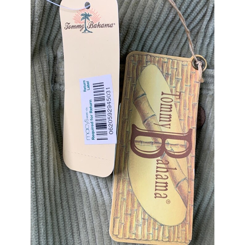 May include: Close-up of a light green corduroy fabric with two tags attached. One tag is cream-colored with the Tommy Bahama logo and Macy's return label. The other tag is brown with the Tommy Bahama logo and bamboo design.