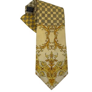 May include: A yellow silk tie with a repeating geometric pattern at the top and a large, ornate gold floral design on the front. The tie is folded over, showing the back and the label.