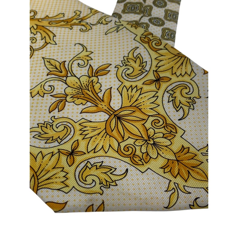 May include: A silk tie with a cream background and a repeating pattern of gold floral and leaf designs. The tie has a classic shape and is suitable for formal or business attire.