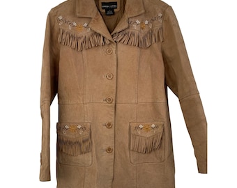 May include: A tan suede jacket with fringe and floral embroidery. The jacket has a collared neckline, button closures, and two front pockets with fringe. The sleeves are long, and the jacket is hanging on a wooden hanger.