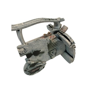 May include: A weathered, gray sculpture with a textured surface and a handle-like structure. The sculpture has a rough, aged appearance with hints of brown and red accents. The design includes carved details and a unique shape.
