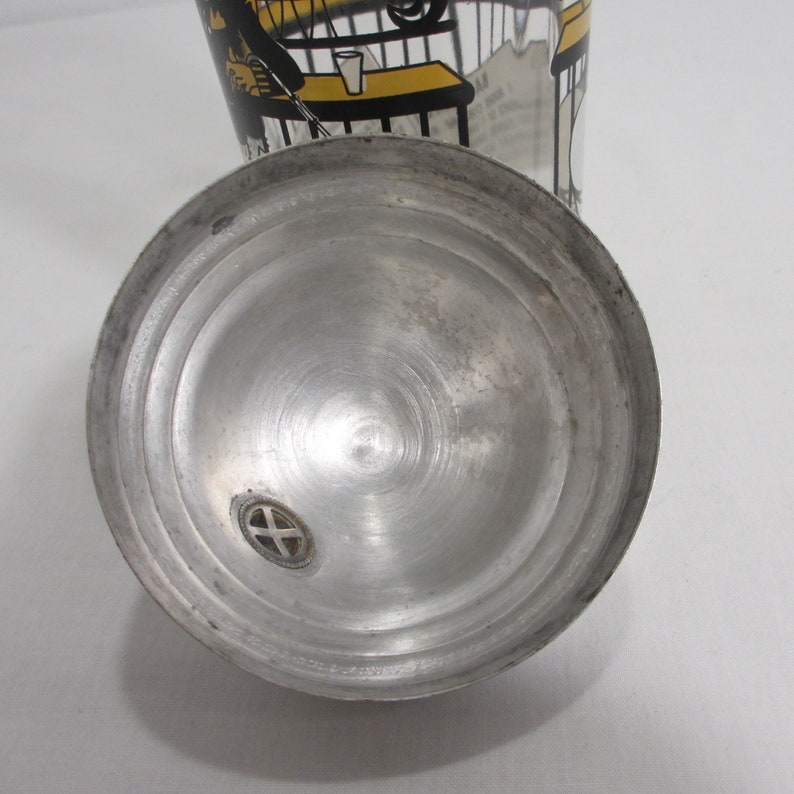 May include: A silver metal shaker lid with a small hole in the centre. The lid has a circular design with concentric circles.