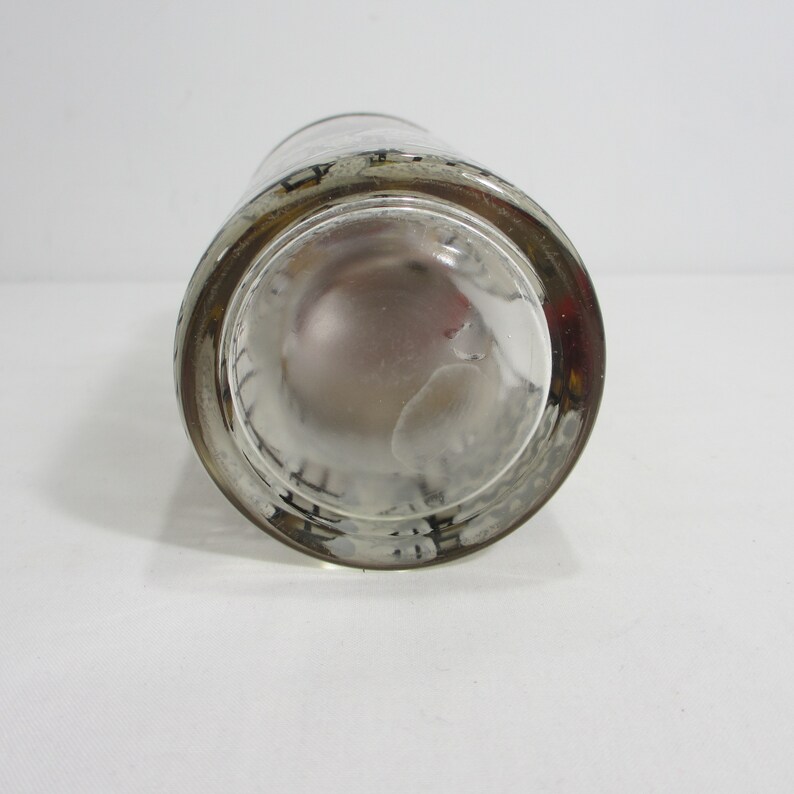 May include: Clear glass shot glass with a black and white design around the rim.