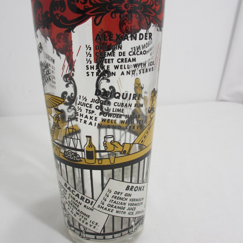 May include: A vintage glass cocktail shaker featuring black and yellow illustrations of people at a bar. The shaker includes recipes for classic cocktails such as Alexander, Daiquiri, Bacardi, and Bronx. The recipes are written in black text on a white background.