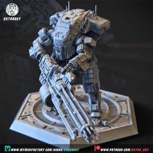 May include: A detailed, grey, 3D-printed model of a bipedal mech robot holding a large gun. The robot stands on a hexagonal platform with a circular design. The model has intricate mechanical details and the text "EXTRAGUY" is visible.