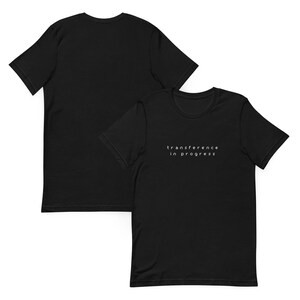 May include: Two black t-shirts, one with the text "transference in progress" printed in white on the front.