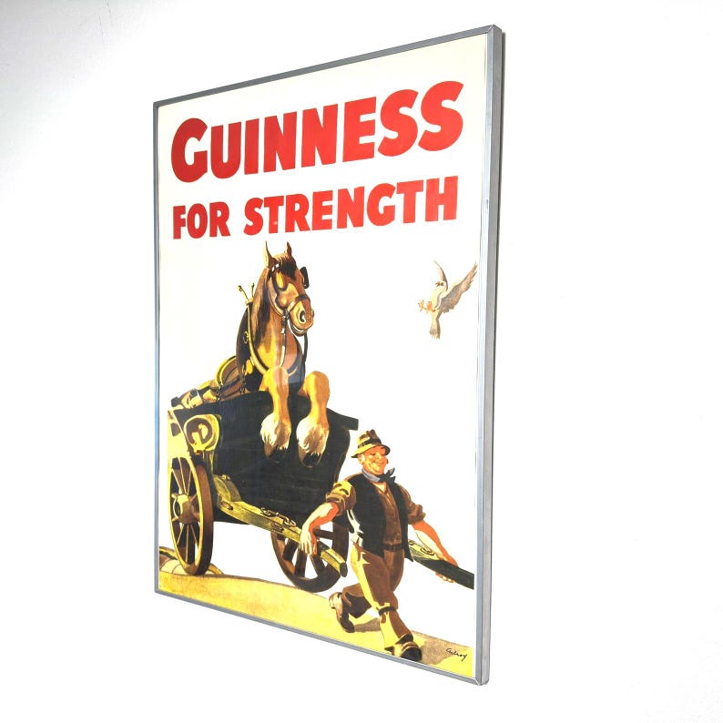 May include: Vintage Guinness advertisement poster with the text "GUINNESS FOR STRENGTH" in red. The image features a horse pulling a cart, a man running alongside, and a dove. The poster has a silver frame.
