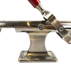 Può includere: Un cavatappi in stile vintage con finitura bronzo. Il cavatappi presenta un manico rosso e un meccanismo a leva. La base è quadrata con angoli arrotondati. Design classico ed elegante.