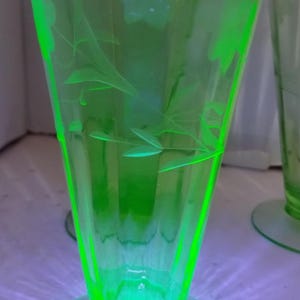 Puede incluir: Un juego de vasos verdes de estilo vintage. Los vasos tienen una forma acampanada con una base redonda y diseños florales grabados. El vidrio brilla intensamente, lo que sugiere que está hecho de vidrio de uranio. Los vasos miden unos 18 cm de alto.