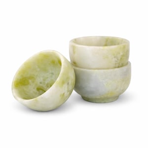 May include: Three small, round bowls made of pale green and white marble. One bowl is tilted on its side, while the other two are stacked. The bowls have a smooth, polished finish and are ideal for serving small portions.