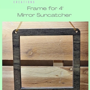 May include: A laser cut frame for a 4 inch mirror suncatcher. The frame is made of wood with a dark gray stain and has a rustic look. The frame has two holes at the top for hanging.