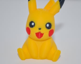 Peut inclure: Une petite figurine jaune représentant une créature aux longues oreilles à pointes noires, aux yeux noirs ronds avec des reflets blancs, aux joues rouges circulaires et à la bouche ouverte montrant une langue rouge. La figurine est assise.