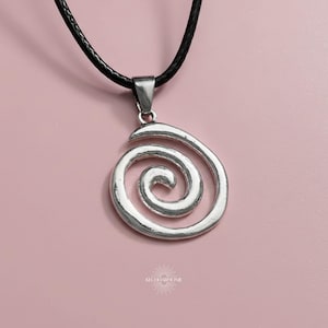 May include: A silver-colored pendant necklace featuring a spiral design. The pendant hangs from a black cord. The background is a solid pink color. The necklace is a simple, elegant accessory.