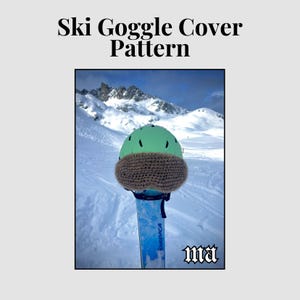 May include: A green ski helmet with a brown knitted goggle cover is placed on a ski, with a snowy mountain in the background. The text at the top says "Ski Goggle Cover Pattern."