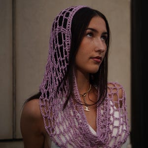 May include: A light purple, open-weave crochet hood and scarf set. The hood covers the head and drapes around the neck, creating a stylish accessory. The set is made of a soft, lightweight yarn, perfect for layering.