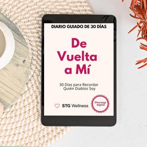 May include: A digital tablet displaying a journal cover with the title "De Vuelta a Mí" in pink, with the text "30 Días para Recordar Quién Diablos Soy" below. The tablet is on a light-colored woven surface.