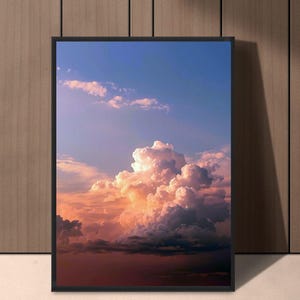 May include: A framed print featuring a vibrant sunset sky with fluffy, illuminated clouds. The artwork showcases a gradient of colors, from deep red at the bottom to a bright blue at the top, creating a dramatic and serene landscape.