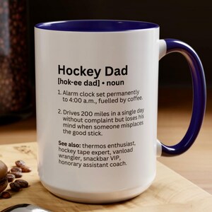 K&ouml;nnte beinhalten: Wei&szlig;er Keramikbecher mit blauem Innenraum und Henkel. Der Becher zeigt den Text "Hockey Dad" mit einer Definition und humorvollen Beschreibungen. Ein tolles Geschenk f&uuml;r Hockey-Fans.