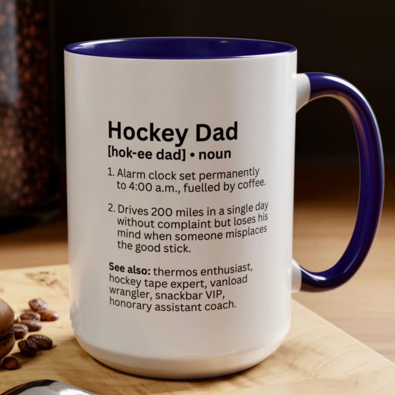 K&ouml;nnte beinhalten: Wei&szlig;er Keramikbecher mit blauem Innenraum und Henkel. Der Becher zeigt den Text "Hockey Dad" mit einer Definition und humorvollen Beschreibungen. Ein tolles Geschenk f&uuml;r Hockey-Fans.