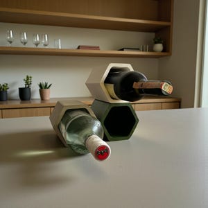 Puede incluir: Un botellero moderno con diseño hexagonal. El botellero es de hormigón y sostiene botellas de vino. Se ve una botella en el botellero y otra botella sobre la superficie. El botellero está en un entorno de cocina.