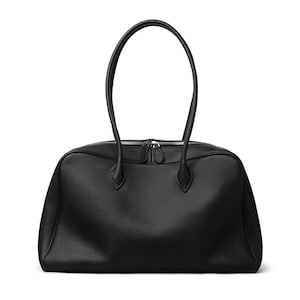 May include: A black leather tote bag with a rectangular shape and two rounded handles. The bag has a zipper closure and a textured surface. The handles are long enough to be carried over the shoulder.