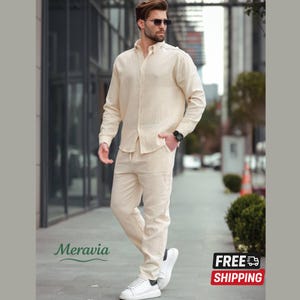 May include: A beige linen two-piece outfit, comprising a long-sleeved shirt and drawstring trousers. The outfit is worn with white trainers. The image includes the text "Meravia" and a "FREE SHIPPING" graphic.
