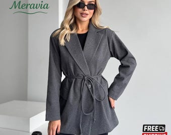 May include: A dark grey blazer with a tie belt, pockets, and a button closure. The blazer is part of a clothing collection and features the brand name "Meravia" in green script. The image also includes a "FREE SHIPPING" graphic.
