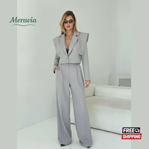 Könnte beinhalten: Ein hellgrauer Damenanzug mit einem cropped Blazer mit strukturierten Schultern und einer Hose mit weitem Bein. Der Blazer hat einen Ein-Knopf-Verschluss. Der Anzug ist aus einem glatten Stoff gefertigt. Das Bild enthält den Text "Meravia" und "FREE SHIPPING".