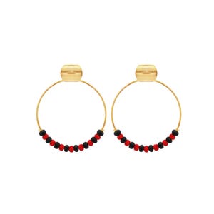 May include: A pair of gold-tone hoop earrings. Each earring features a gold-colored stud and a circular hoop adorned with alternating red and black beads. The earrings are displayed against a white background.