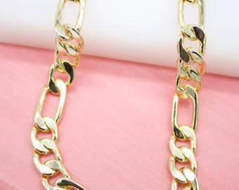 May include: Gold-colored chain necklace with a Figaro link design. The necklace features alternating elongated and rounded links, creating a bold and stylish accessory. The chain is displayed against a pink background.