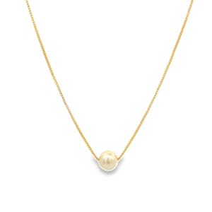 Könnte beinhalten: Eine goldfarbene Halskette mit einem einzelnen, großen, cremefarbenen Perlenanhänger. Die Kette ist filigran und scheint aus kleinen, quadratischen Gliedern zu bestehen. Die Perle ist rund und zentriert, wodurch ein schlichtes, elegantes Design entsteht.