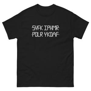 Peut inclure: T-shirt noir avec texte blanc pixélisé. Le texte se lit "SYFK IPHMR. POLR YKDAF." Le t-shirt a des manches courtes et un col rond.
