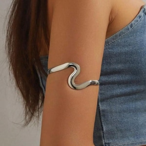 May include: Silver-toned metal arm cuff with a wavy design.