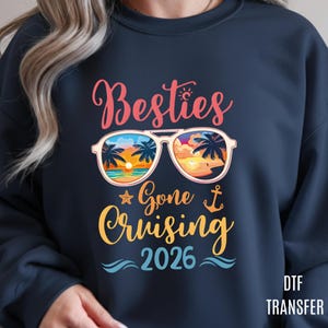May include: Navy blue sweatshirt with the words "Besties Gone Cruising 2026" in a colorful design. The design includes sunglasses with a beach scene, a starfish, and an anchor.
