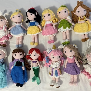 以下が含まれることがあります： 12体の手作りの編み人形のコレクションで、それぞれ異なるプリンセスキャラクターを描いています。人形は、青、黄、ピンク、緑など、さまざまな色で、詳細な衣装とヘアスタイルが特徴です。人形の高さは約15cmです。