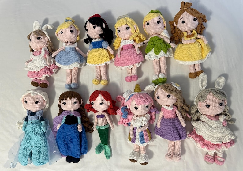 以下が含まれることがあります： 12体の手作りの編み人形のコレクションで、それぞれ異なるプリンセスキャラクターを描いています。人形は、青、黄、ピンク、緑など、さまざまな色で、詳細な衣装とヘアスタイルが特徴です。人形の高さは約15cmです。