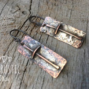 Puede incluir: Un par de pendientes de cobre martillado con un dise&ntilde;o de cruz. Los pendientes son de color plateado r&uacute;stico con un acento de cobre.