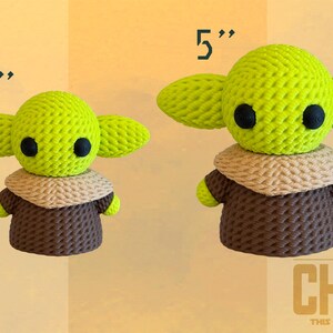 May include: Two crocheted figures of The Child, one 3 inches tall and the other 5 inches tall. The figures have large green ears, black eyes, and wear brown robes with tan collars. The text "THE CHILD" and "THIS IS THE WAY" is in the lower right corner.