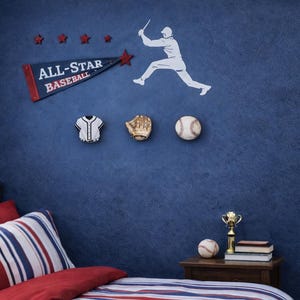 May include: A blue wall featuring a baseball-themed wall decal set with a white silhouette of a batter, a blue pennant with the text ALL-STAR BASEBALL, and three wall-mounted decor pieces shaped like a jersey, a baseball glove, and a baseball.
