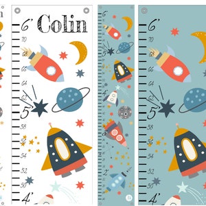 May include: A white and a blue growth chart with a space theme. The chart features a rocket, stars, planets, and a crescent moon. The chart is labeled with inches and feet. The name "Colin" is written at the top of the chart.