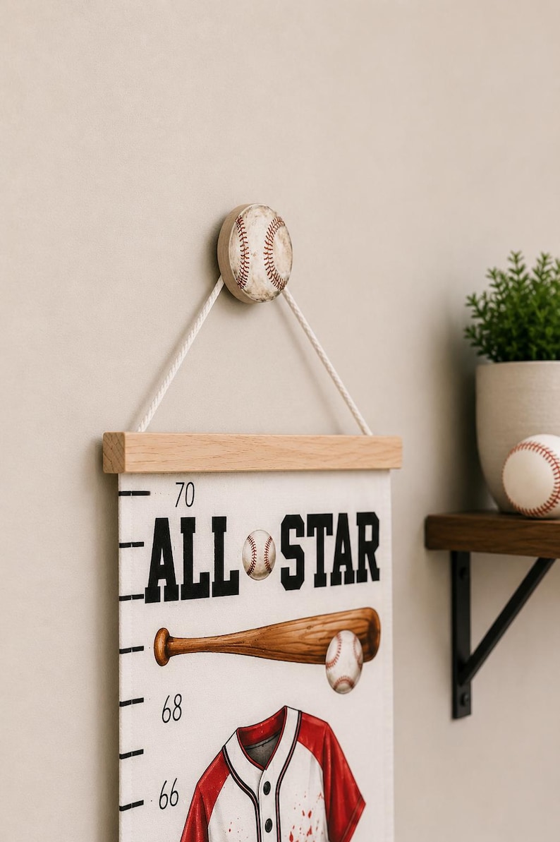May include: A white canvas growth chart hanging from a baseball-shaped wooden knob with a white rope. The chart features the text ALL STAR, a wooden baseball bat, a baseball, and a red and white baseball jersey with measurement markings.