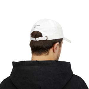 May include: White baseball cap with a curved brim and adjustable strap. The cap has the text "Add your initials or Title here" printed on the back. The cap is worn by a person wearing a black hoodie.