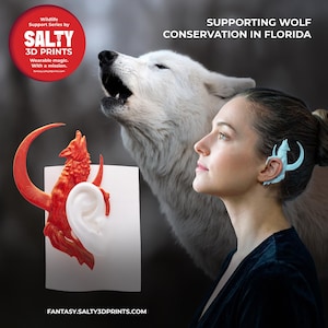 May include: An image promoting wolf conservation in Florida. It features a woman wearing a light blue ear cuff with a wolf design. A 3D-printed red wolf sculpture is displayed next to a white ear. The Salty 3D Prints logo is in the upper left.