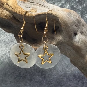 May include: A pair of gold star earrings with white shell-like round pendants.