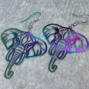 May include: A pair of iridescent silver earrings shaped like elephants. The earrings are made of metal and have a detailed design.