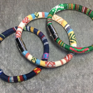 May include: Three colorful woven bracelets with metal clasps. The bracelets are made of different colored threads and have a variety of patterns.