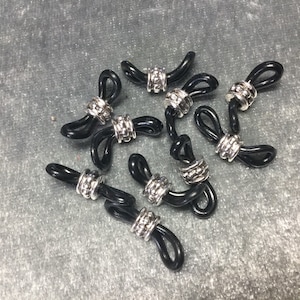 May include: A group of eight black and silver eyeglass holders. Each holder has a silver bead with a textured design.