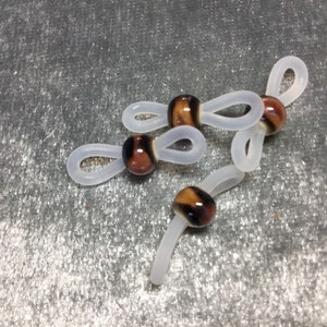May include: Three clear plastic eyeglass retainers with brown and black striped glass beads.