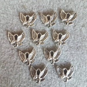 May include: Twelve silver eagle charms with a spread wing design. The charms are perfect for jewelry making, scrapbooking, and other craft projects.